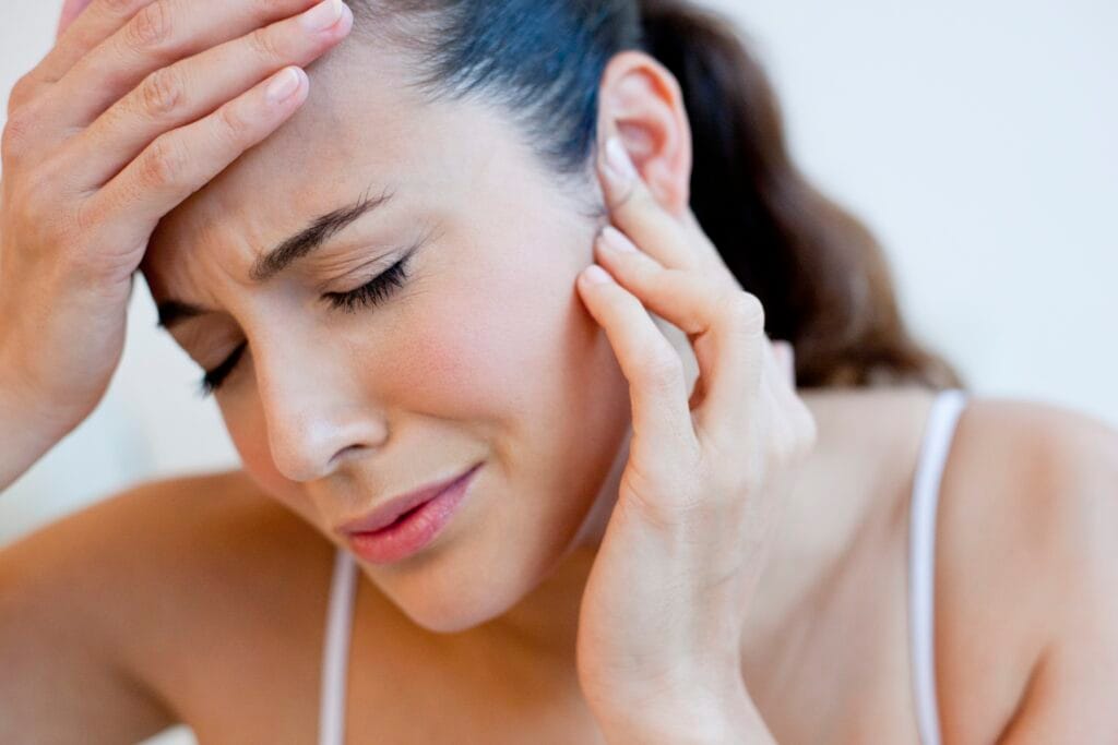 Woman touching her head and ear with earache.